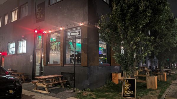 Restaurant de soir avec un éclairage rouge, affiche La Part des Anges visible, montrant l'intérieur chaleureux et accueillant.