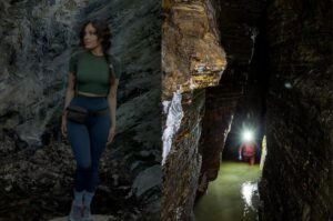 Femme en tenue de randonnee devant une paroi rocheuse a cote d'un speleologue explorant une grotte etroite et sombre avec une lampe frontale.